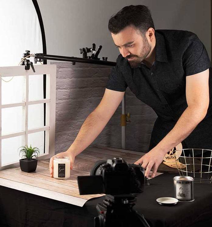 Regal Fierce Media photographer arranging a candle on a tabletop set in front of a camera